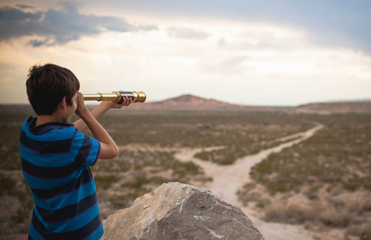 boy-looking-through-telescope-in-desert