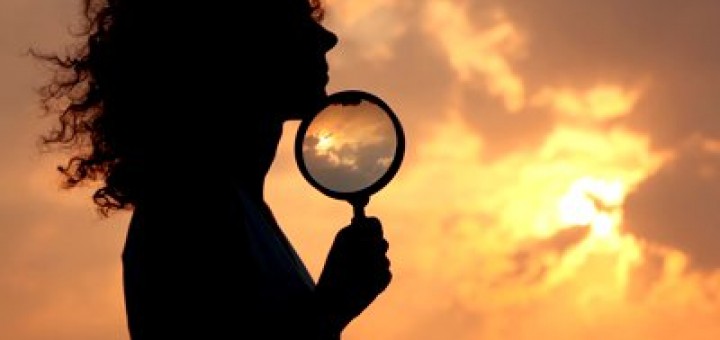 stock-footage-woman-holds-magnifier-and-puts-it-to-chin-against-sky-and-sun-720x340